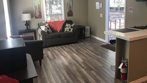 A furnished living area with a sofa, a table, a lamp, a TV, and a fire extinguisher. - Sunburst RV Resort (Milton)