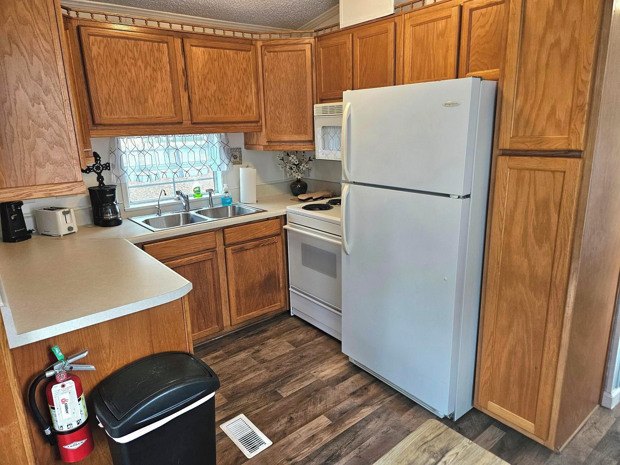 A kitchen with wooden cabinets, a white refrigerator, a stove, and a sink.