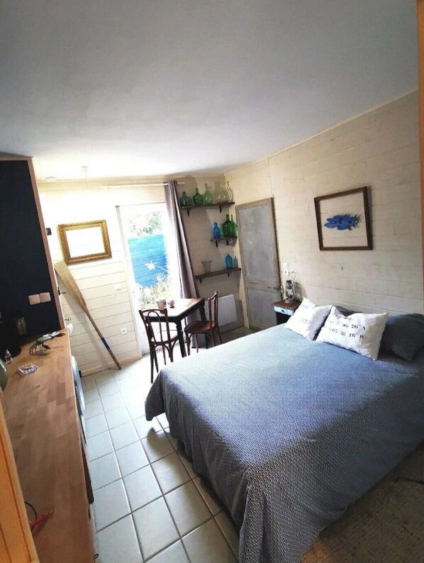Un dormitorio con cama, escritorio, sillas, ventana con vistas y una puerta.