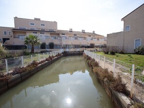 A residential area with a narrow water channel, white fences, and buildings with balconies. - Les Marines du Levant by Interhome (Hyères)