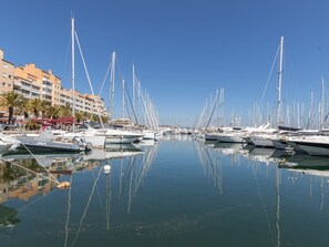 A marina with numerous sailboats docked in calm waters, surrounded by buildings and palm trees. - Les Marines du Levant by Interhome (Hyères)