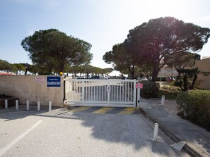 A gated entrance with a sign indicating private property, a parking area with vehicles, and a clear sky. - Les Marines du Levant by Interhome (Hyères)