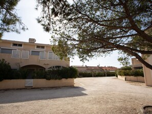 A building with a beige facade, arched windows, and a gravel driveway. - Les Marines du Levant by Interhome (Hyères)