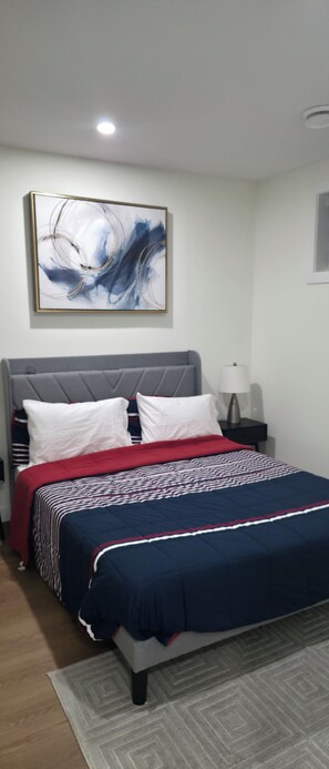 A bedroom with a bed, a nightstand, a lamp, a wall art piece, and a ceiling light. - New Cozy One bed Suite  close to downtown Edmonton.For Leisure and Business Stay (Northwest)