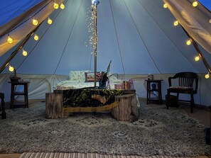 Una carpa con una mesa central, sillas y luces colgantes.