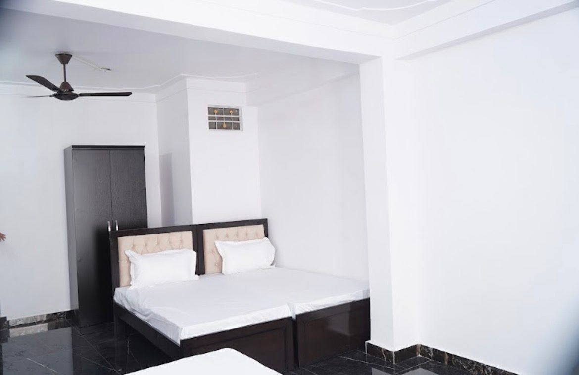 Una habitación de hotel con cama, ventilador de techo, armario y una ventana pequeña.