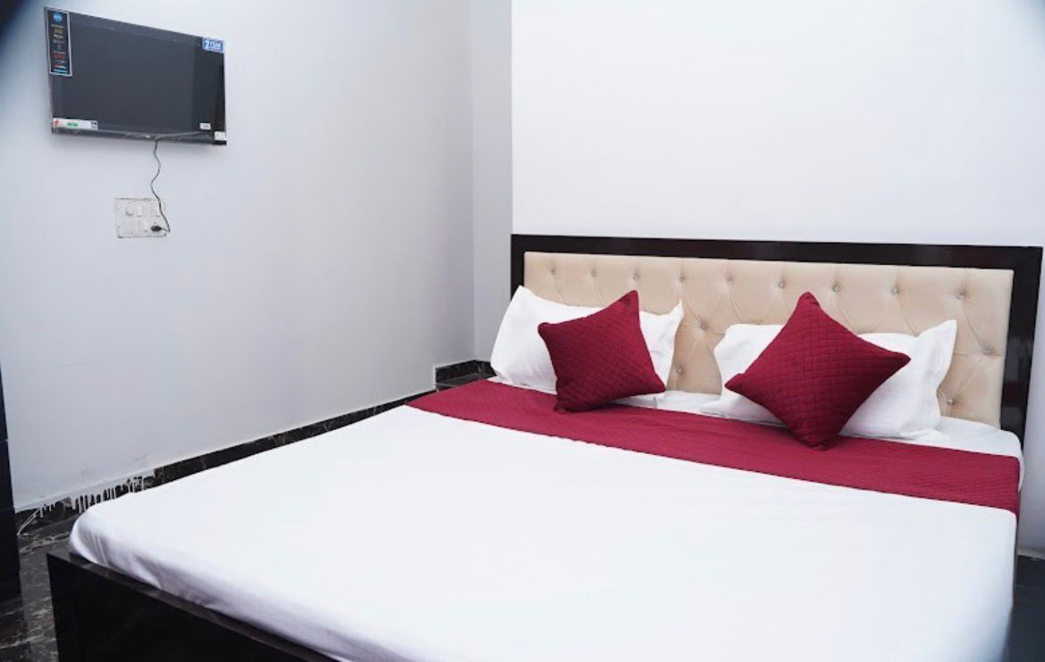 A bed with a tufted headboard, two red pillows, and a white bedspread.