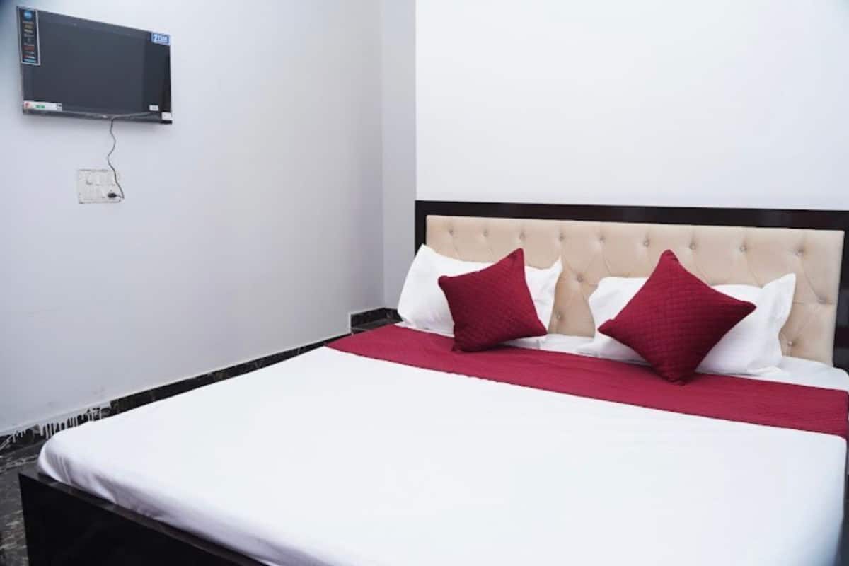 A bed with a tufted headboard, two red pillows, and a white bedspread.