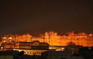 A historic building with multiple levels and domes, illuminated at night. - Shri daulat villas hotel (Udaipur)