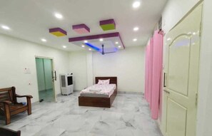 A bedroom with a bed, a bench, a wardrobe, a door, and a ceiling fan. - Hotel Tene & Resort (Daporijo)