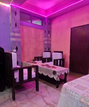 Une piĂšce comprenant une table Ă manger, quatre chaises, un lit et une porte.