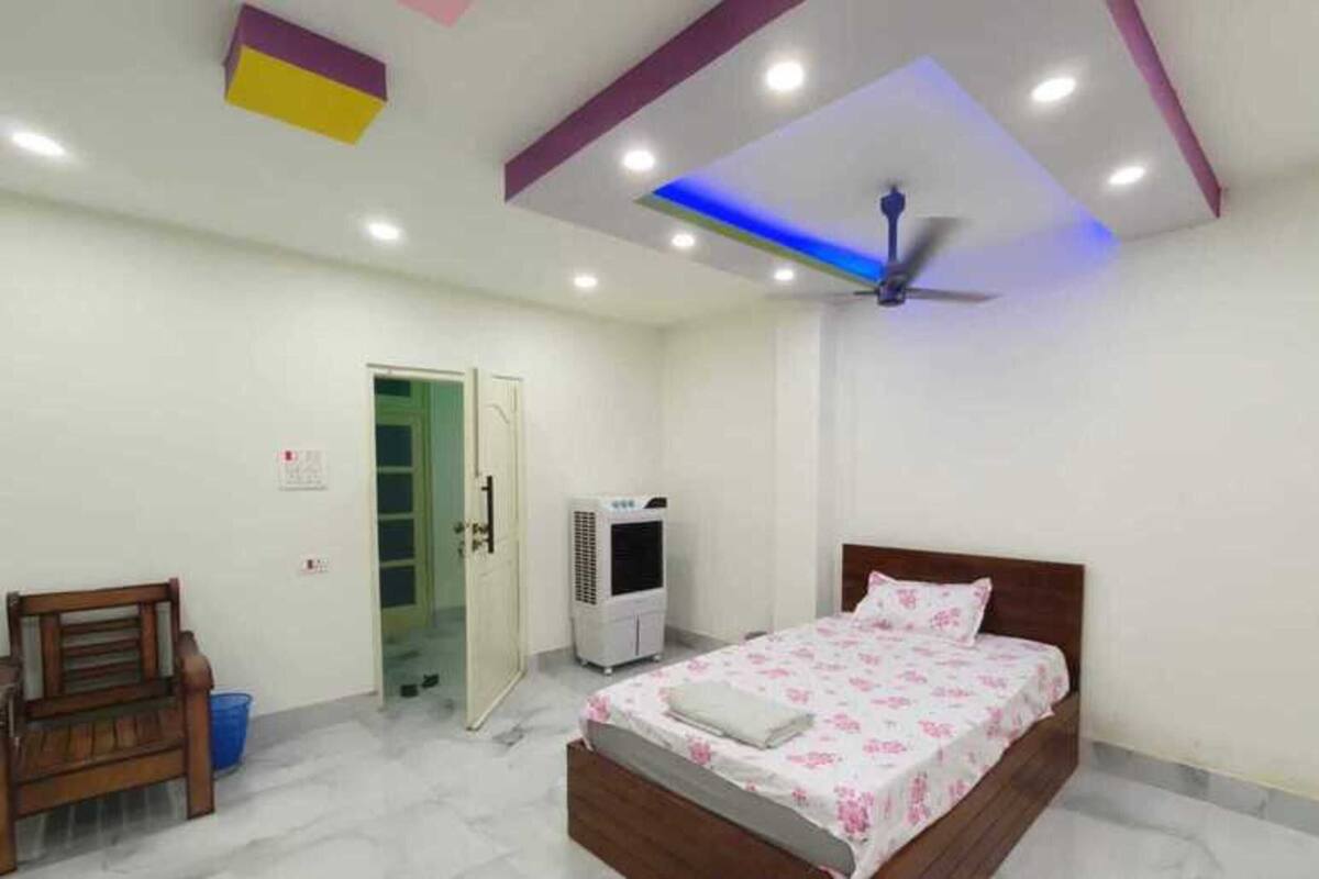 A bedroom with a bed, a ceiling fan, an air conditioner, and a bench.