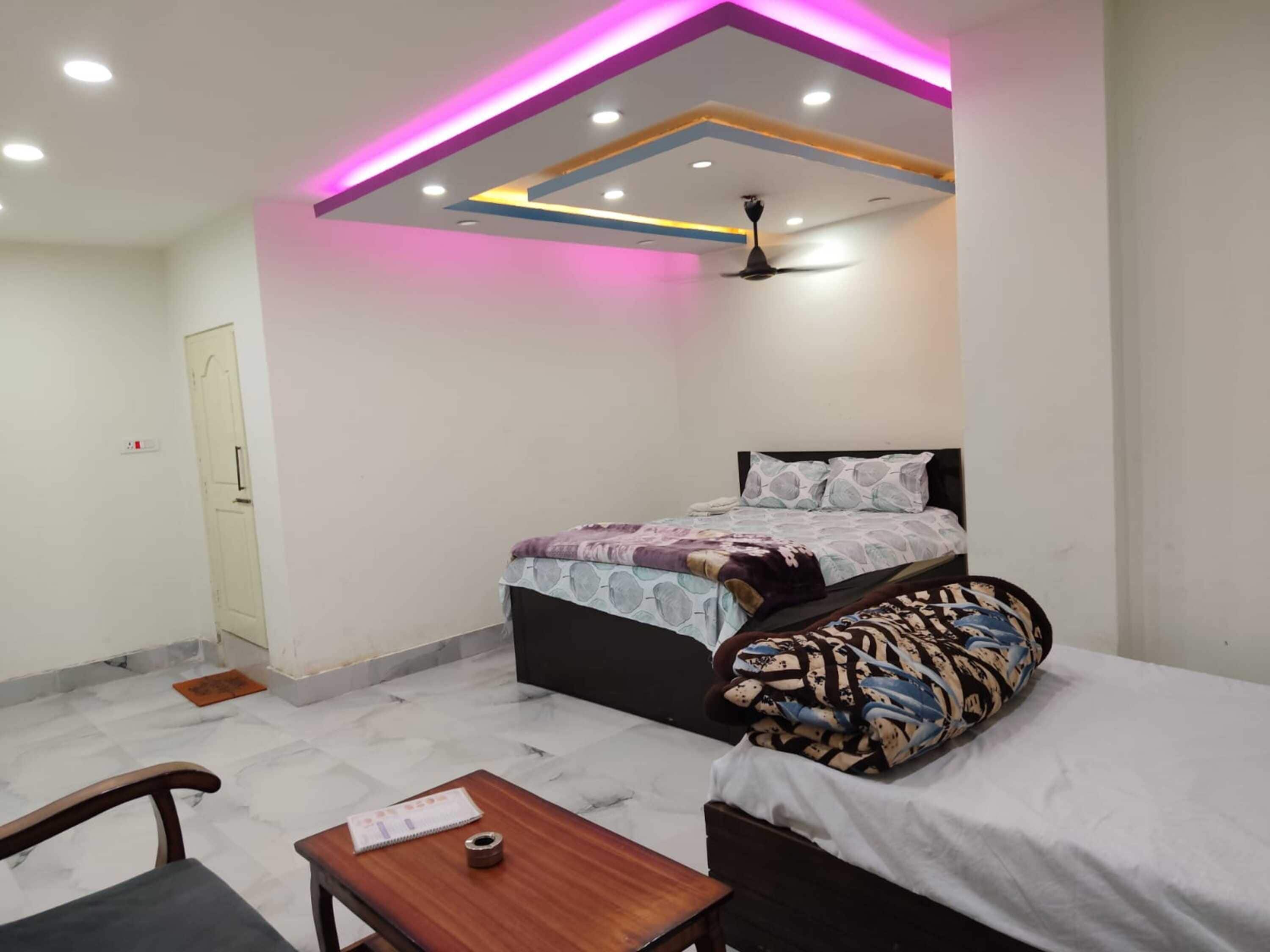 A bedroom with a bed, a desk, a chair, a ceiling fan, and a door.