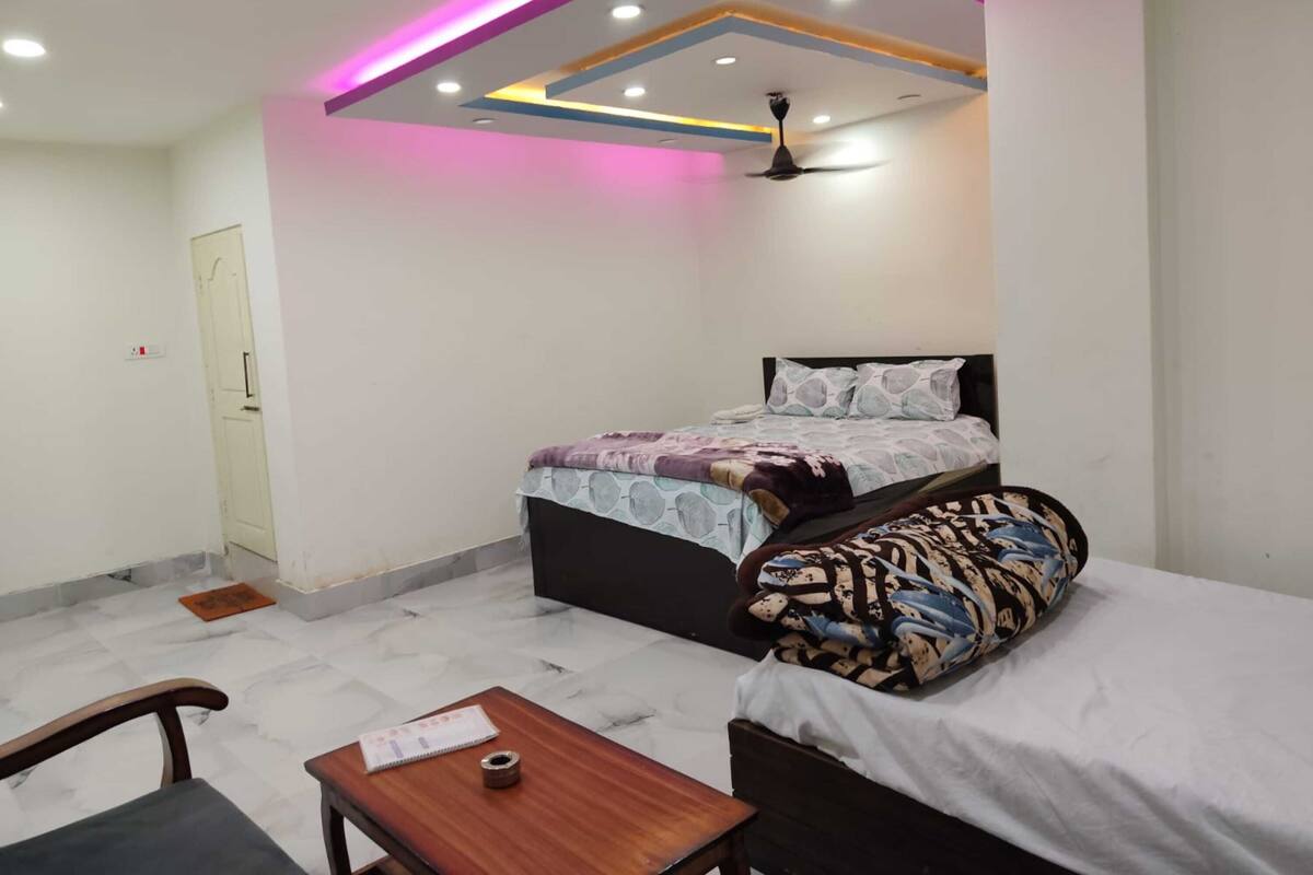 A bedroom with a bed, a desk, a chair, a ceiling fan, and a door.