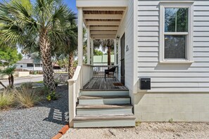A house with a porch, steps, and a palm tree.
