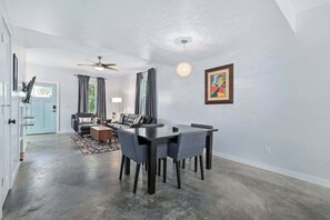 A dining area with a table and chairs, a ceiling fan, and a painting on the wall.