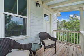 A covered porch with wicker furniture, a small table, and a view of greenery. - Lincolnville Charm l Walk to DNTN l Dog Friendly (St. Augustine)