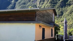 Ein Gebäude mit einem geneigten Dach, einer kleinen Veranda und Blick auf eine gebirgige Landschaft.