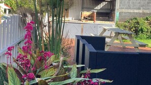 Eine Holterrasse mit Grillplatz, umgeben von Pflanzen und Blick auf die Berge.