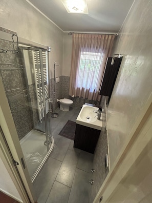 Ein Badezimmer mit Duschkabine, Toilette und Waschbecken mit Spiegel.