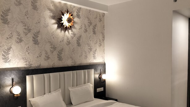 Un dormitorio moderno con una cama grande, cabecera oscura y apliques decorativos.