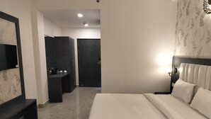 Una habitación de hotel con una cama, un escritorio, un espejo y un armario.