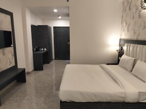 Hotellihuone, jossa on sänky, työpöytä, peili ja vaatekaappi.