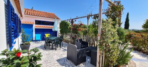 A patio with outdoor furniture, a pergola with climbing plants, and a building with blue shutters. - Fully equipped rental, close to everything. Quiet (Obidos)