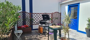 A patio with a grill, a small table, potted plants, and a blue door. - Fully equipped rental, close to everything. Quiet (Obidos)