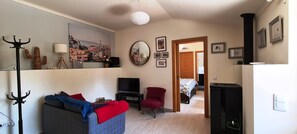 A living room with a sofa, a red armchair, a television, a cactus, and a painting of a cityscape. - Fully equipped rental, close to everything. Quiet (Obidos)