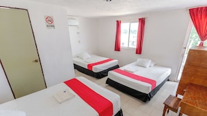 Une chambre d’hôtel avec deux lits, un bureau en bois, une fenêtre avec des rideaux rouges et un panneau indiquant « Il est interdit de fumer ».