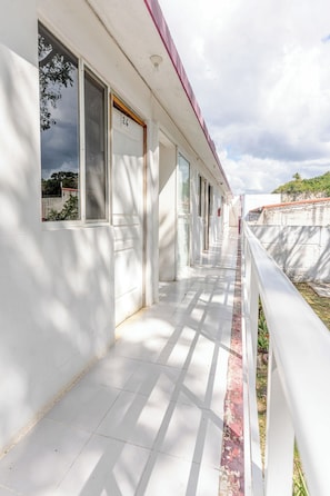 Un pasillo con paredes blancas, techo rojo y una ventana con el número 26.