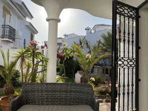 A covered outdoor seating area with a wicker chair, surrounded by potted plants and a decorative gate. - 50 Beautiful Mijas Playa Club (La Cala de Mijas)