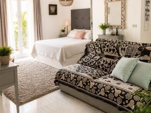 A bedroom with a bed, a sofa, a bedside table, a mirror, and a window. - 50 Beautiful Mijas Playa Club (La Cala de Mijas)