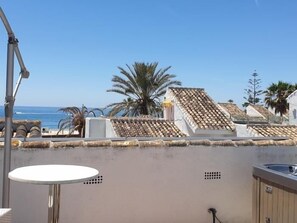 Eine Dachterrasse mit Meerblick, einem weißen Tisch und einem Wasserspiel.