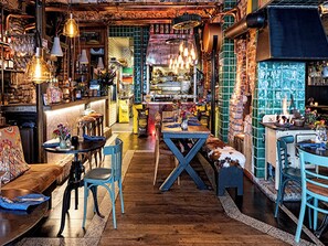 Um restaurante acolhedor com soalho de madeira, cadeiras azuis e luzes pendentes.