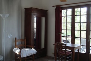 Ein Zimmer mit Holzstuhl, Tisch, Spiegel und einem fensterbepflanzten Fenster.