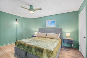A bedroom with a bed, a ceiling fan, a nightstand, a lamp, and a window. - Nurses & Military Stays Near Ft Campbell + Vanderbilt Health + APSU (Clarksville)