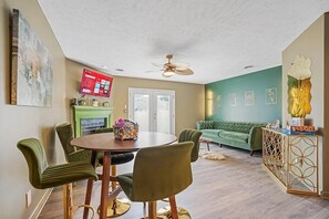 A dining area with a round table and chairs, a green sofa, and a decorative console. - Nurses & Military Stays Near Ft Campbell + Vanderbilt Health + APSU (Clarksville)