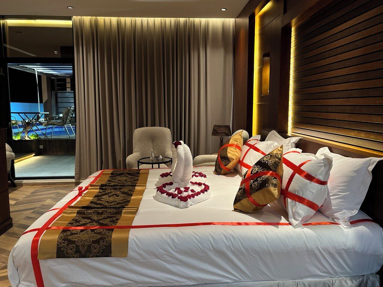 Een hotelkamer met een bed, een stoel, een tafel en uitzicht op een zwembad.