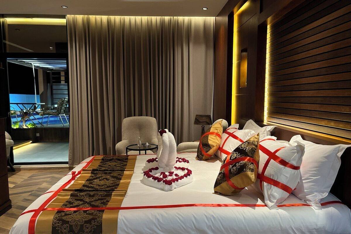 Quarto de hotel com cama, poltrona, mesa e vista para piscina.