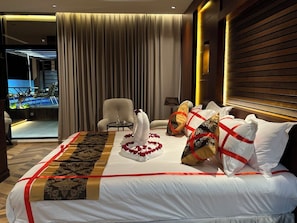 A hotel room with a bed, a chair, a table, and a view of a pool.