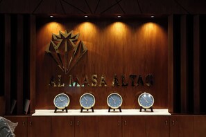 A reception desk with a wooden backdrop, a logo, and four clocks.