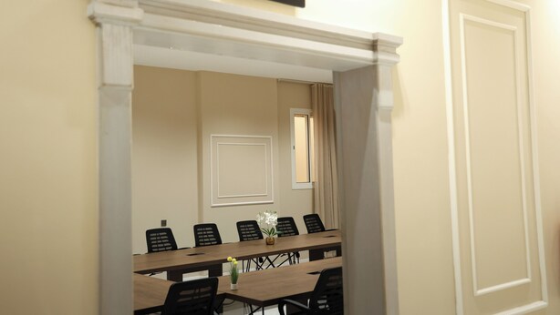A meeting room with a long table, chairs, a potted plant, and a sign indicating it's a meeting room. - Al Masa Al Taj Hotel Apartments (Ha'il)