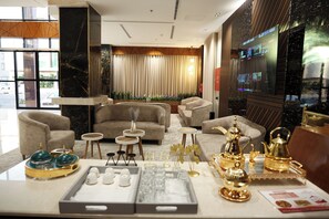 Een moderne hotel lobby met een zithoek, een receptiebalie en een groot scherm met content.