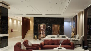 A spacious lobby with a marble reception desk, a staircase, and a seating area with sofas and armchairs. - Al Masa Al Taj Hotel Apartments (Ha'il)