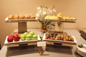 Un buffet proposant une variété de fruits et de pùtisseries.