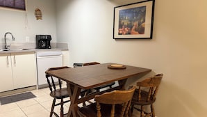 A compact kitchen with a dining table, chairs, a coffee maker, and a dishwasher. - Bright 2BR BSMT Suite NR UofC n Foothills Hospital (Calgary)