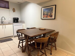 A compact kitchen with a dining table, chairs, a coffee maker, and a dishwasher.