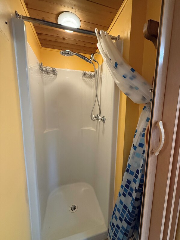 A shower with a glass door, a showerhead, and a drain.